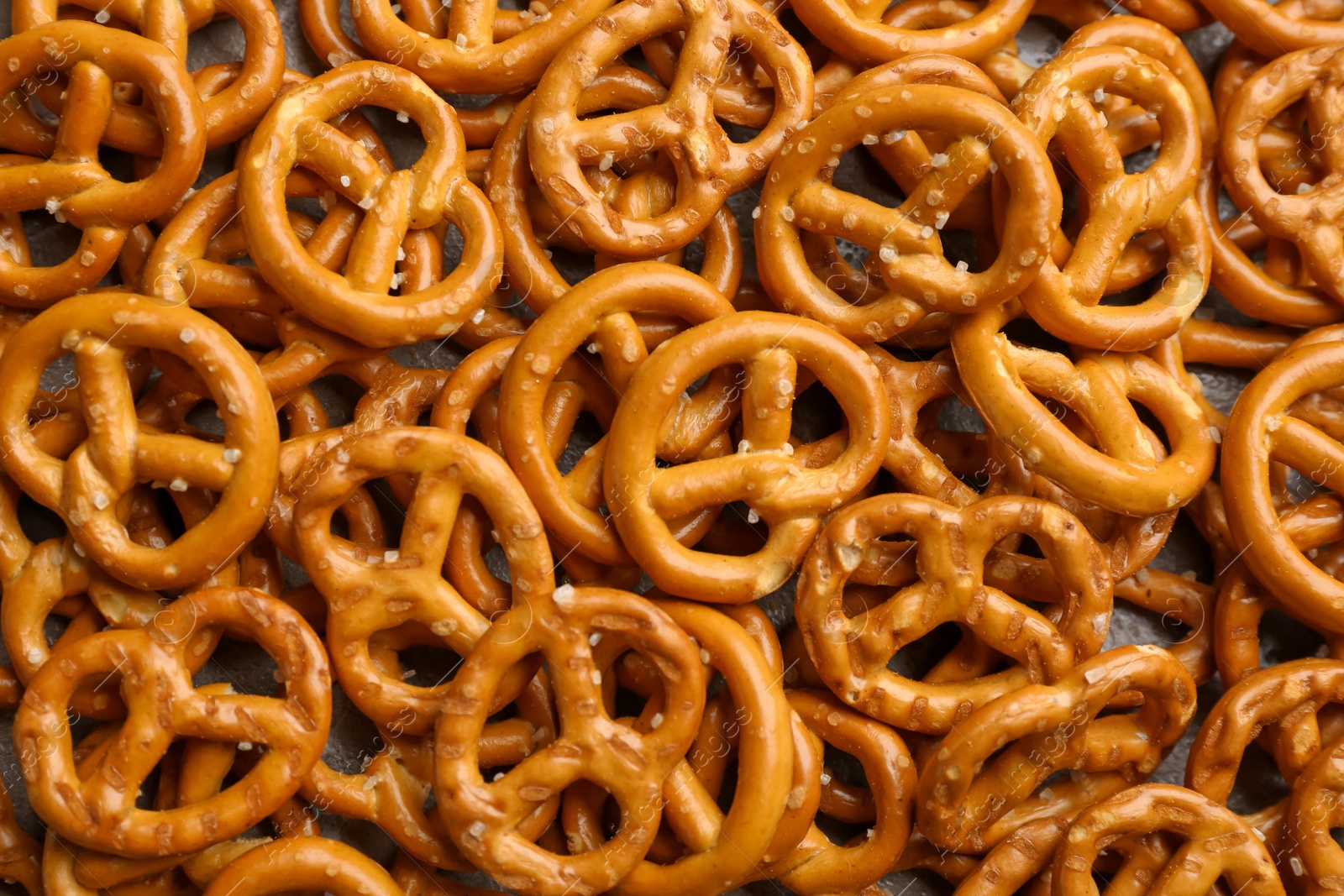 Photo of Many delicious pretzel crackers as background, top view