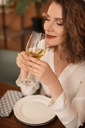 Photo of Woman with glass of wine at table in restaurant