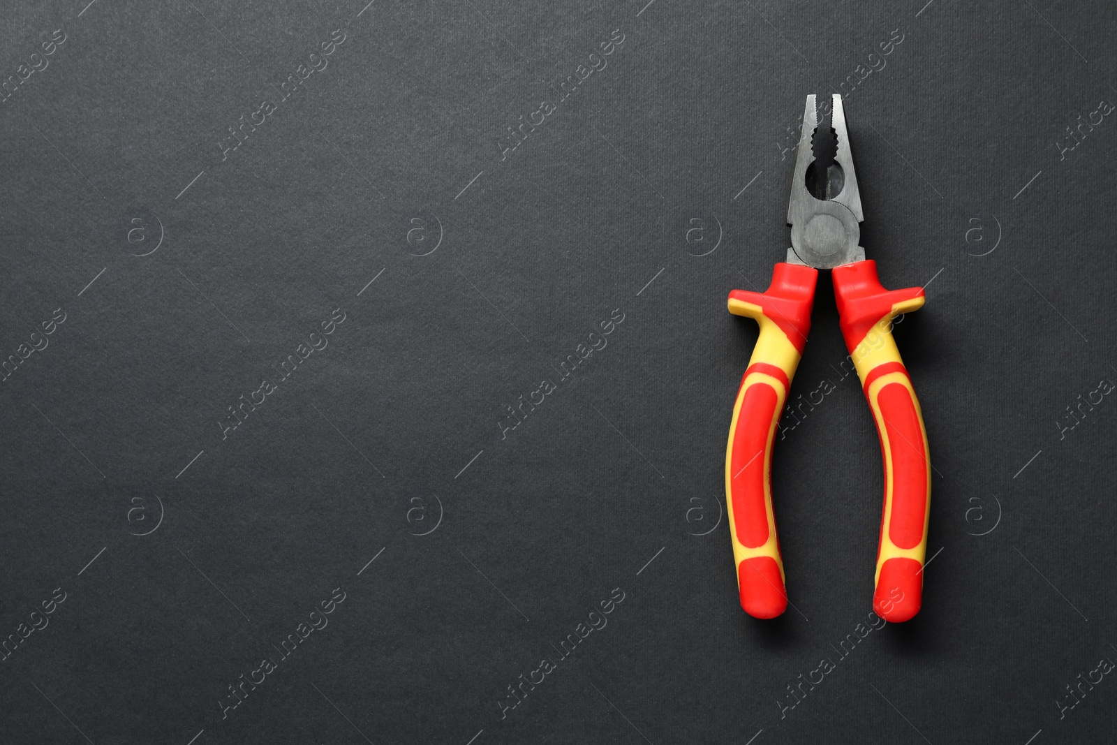 Photo of Combination pliers on black background, top view. Space for text