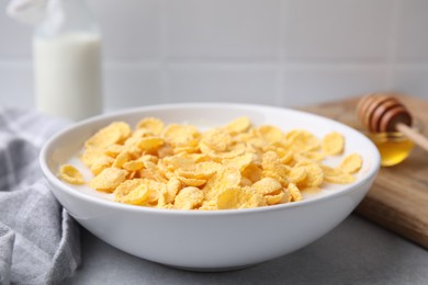 Photo of Breakfast cereal. Corn flakes and milk in bowl on light grey table, closeup