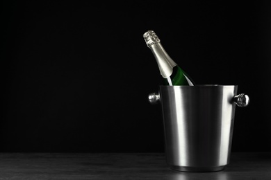 Photo of Bottle of champagne in bucket on black background. Space for text