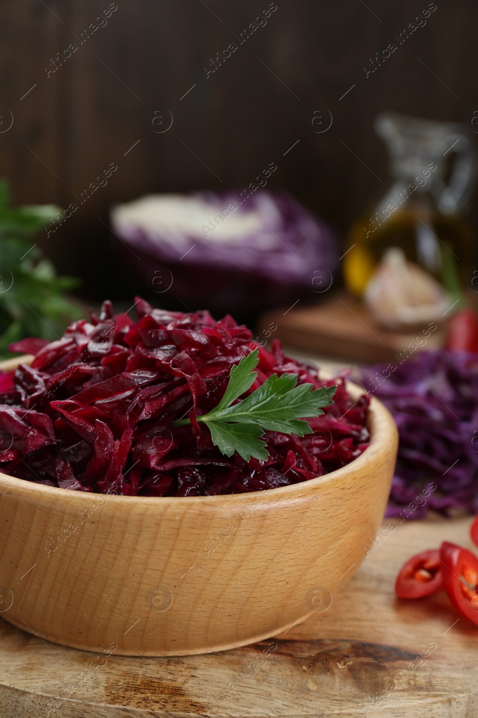 Photo of Tasty red cabbage sauerkraut with parsley on wooden table, closeup