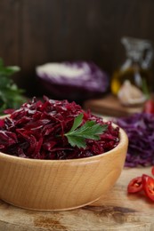 Photo of Tasty red cabbage sauerkraut with parsley on wooden table, closeup