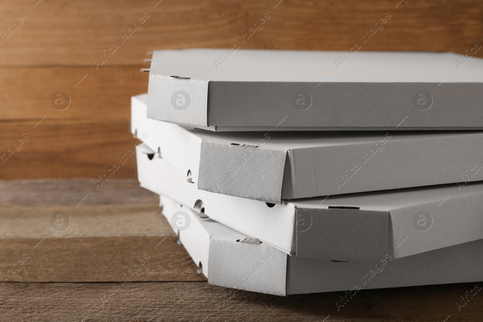 Photo of Stack of empty pizza boxes on wooden table, closeup. Space for text
