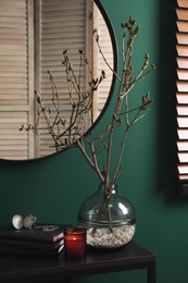 Photo of Beautiful tree twigs in vase on table near green wall