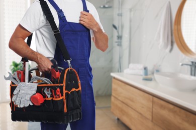 Plumber with bag of instruments in bathroom, closeup. Space for text