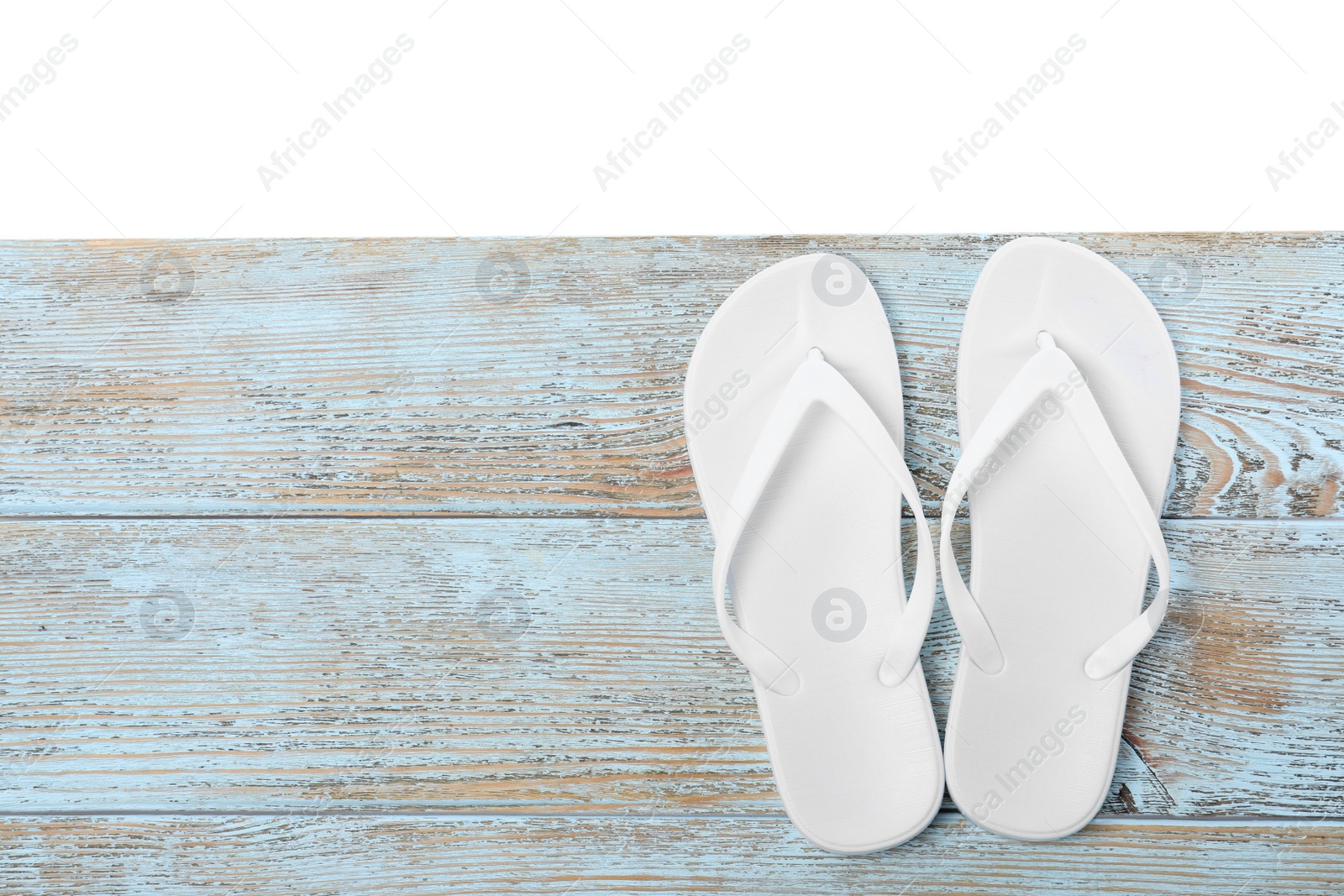 Photo of Bright flip flops and space for text on light wooden table against white background, top view