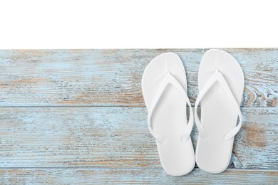 Bright flip flops and space for text on light wooden table against white background, top view