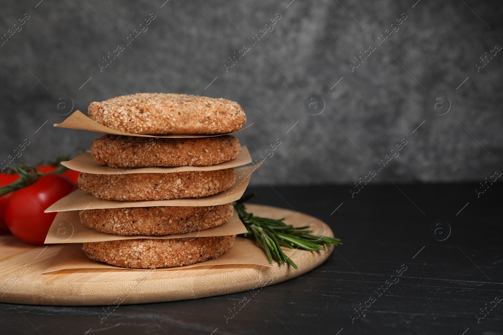 Photo of Raw vegan cutlets with breadcrumbs on black table, space for text