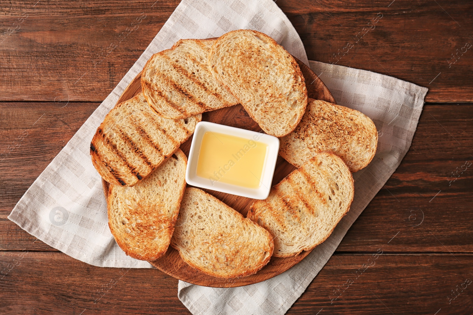 Photo of Board with toasted bread and honey on wooden table, top view