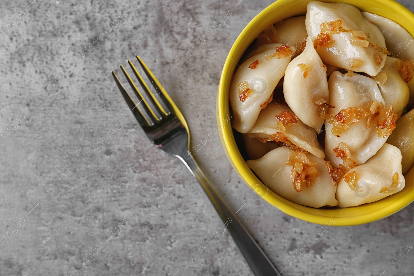 Photo of Delicious cooked dumplings with fried onion on grey table, flat lay. Space for text