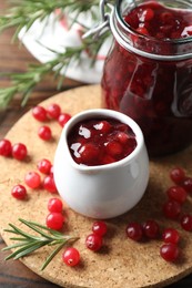 Photo of Cranberry sauce, fresh berries and rosemary on table