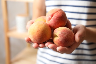 Photo of Woman holding delicious juicy ripe peaches, closeup