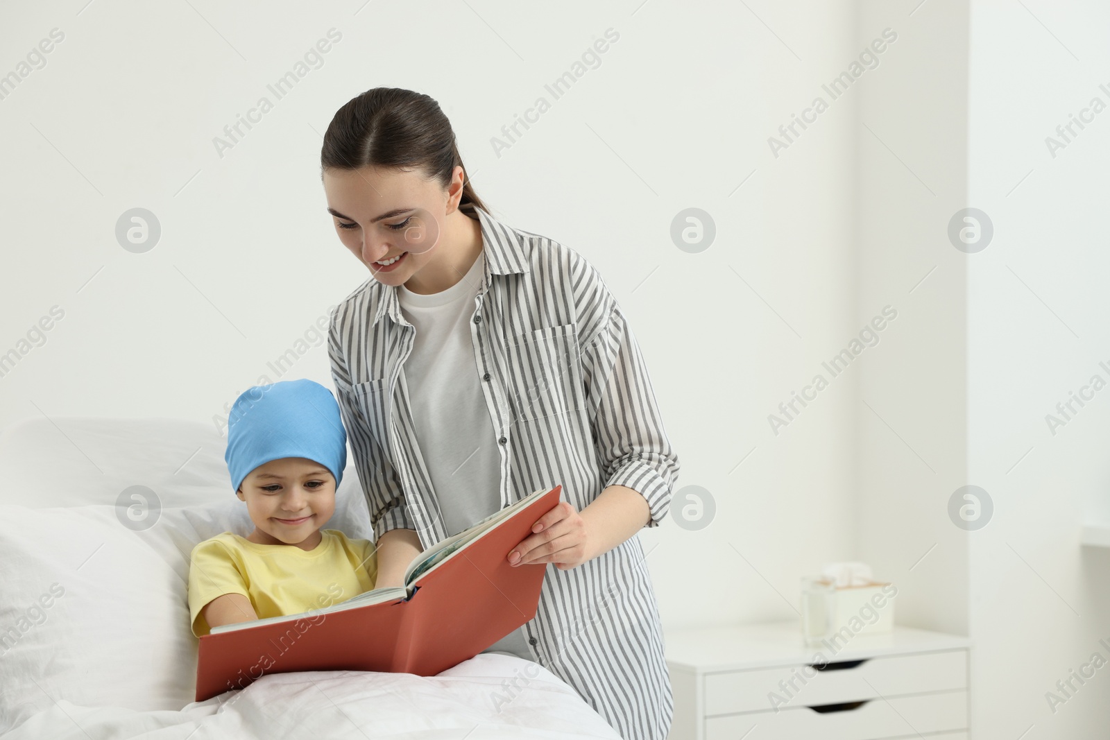 Photo of Childhood cancer. Mother and daughter reading book in hospital