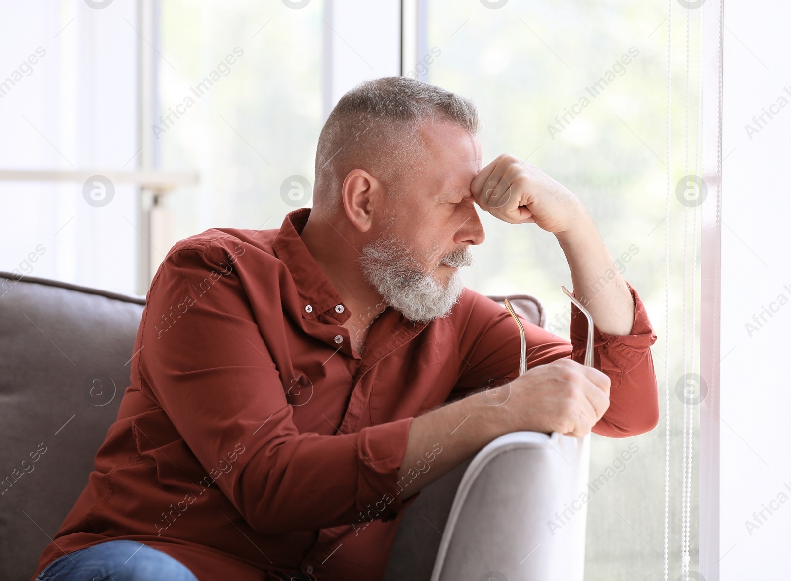 Photo of Depressed senior man sitting in armchair indoors