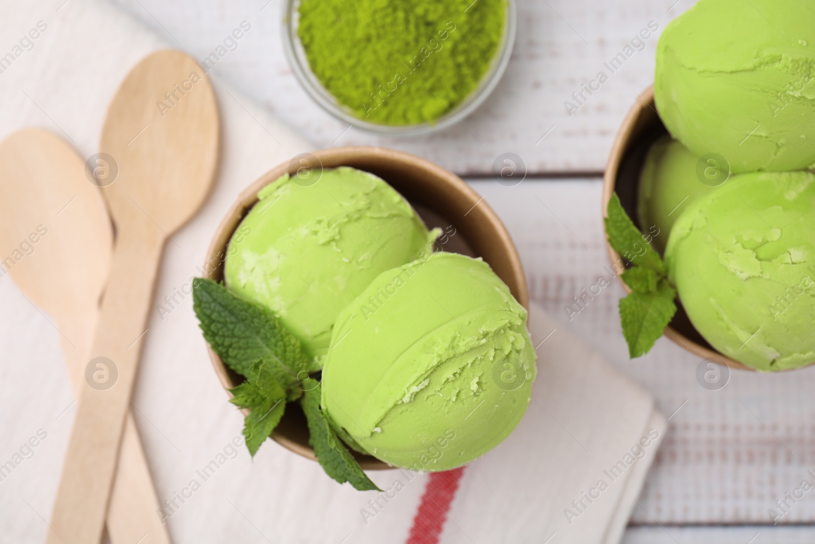 Photo of Paper cups with tasty matcha ice cream on white wooden table, flat lay