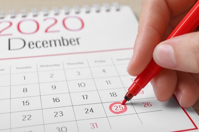 Photo of Woman marking date in calendar, closeup. Christmas countdown