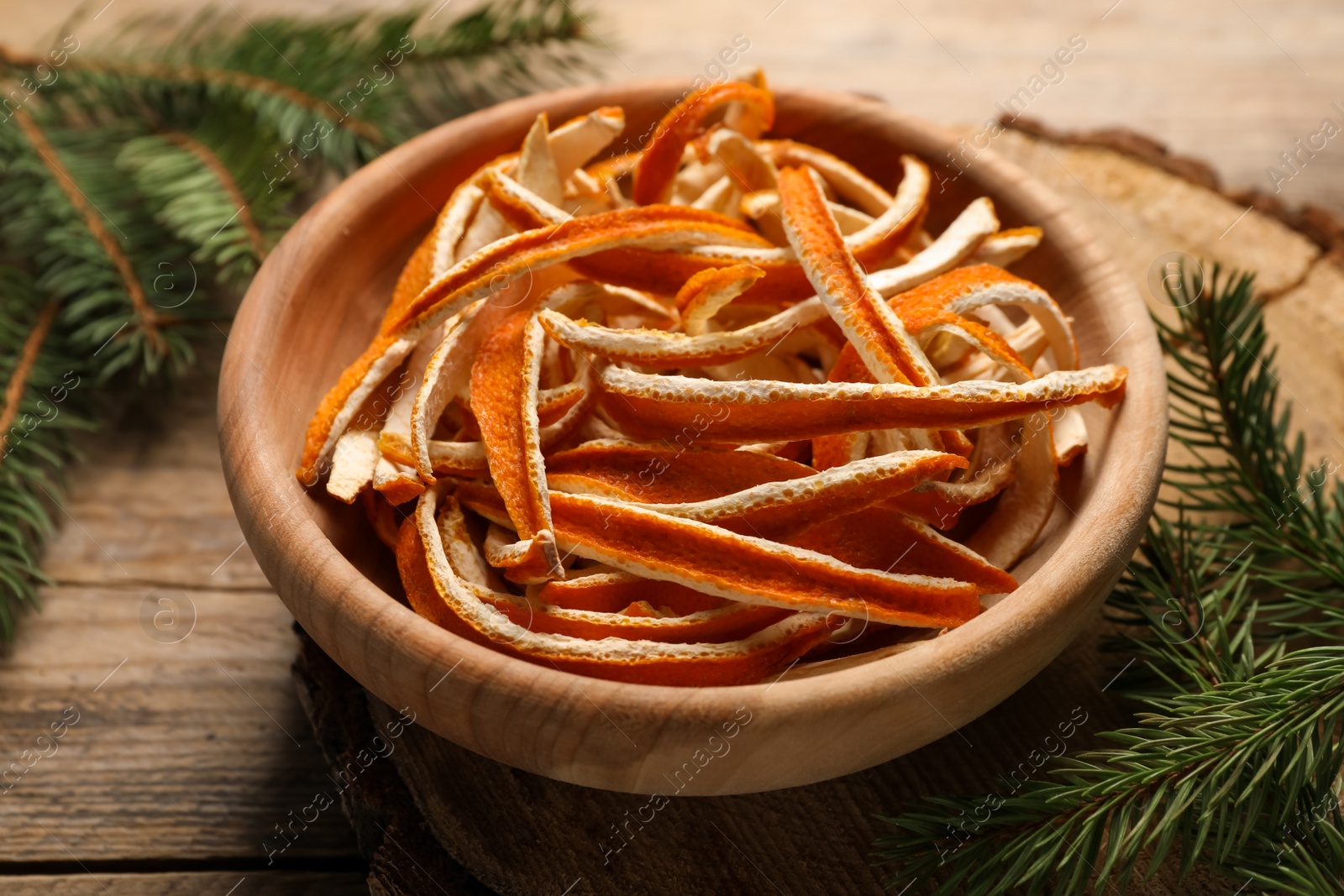 Photo of Dry orange peels and fir branches on wooden table, closeup