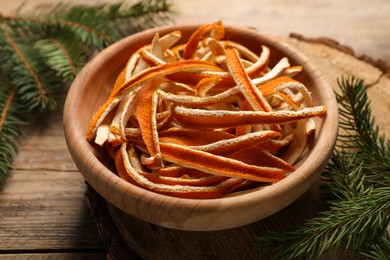 Photo of Dry orange peels and fir branches on wooden table, closeup