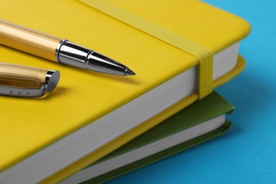 Photo of Ballpoint pen and notebooks on light blue background, closeup