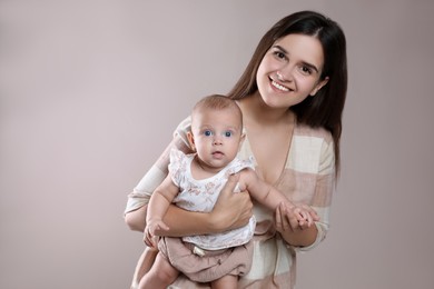 Beautiful mother with her cute baby on beige background