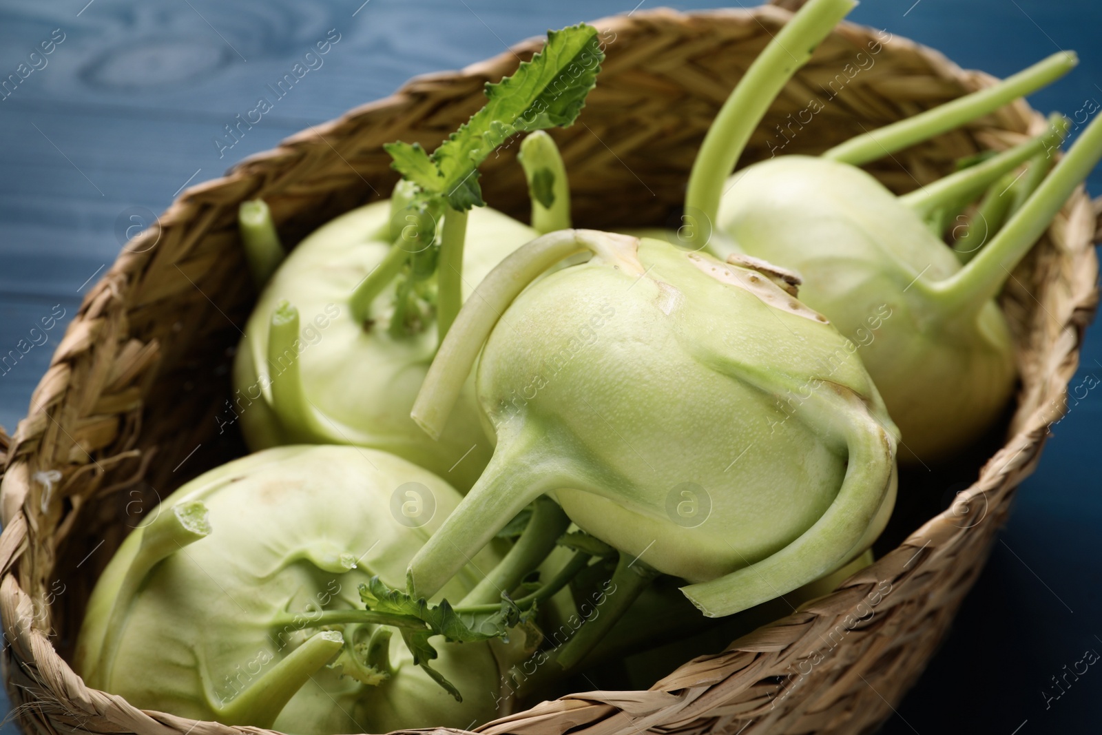 Photo of Whole ripe kohlrabi plants in wicker basket, closeup