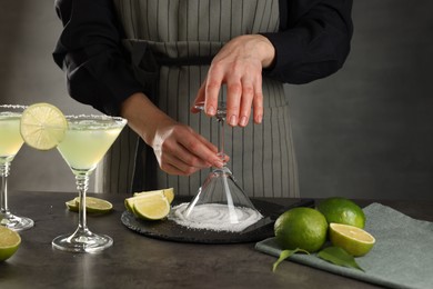 Woman making delicious Margarita cocktail at grey table, closeup