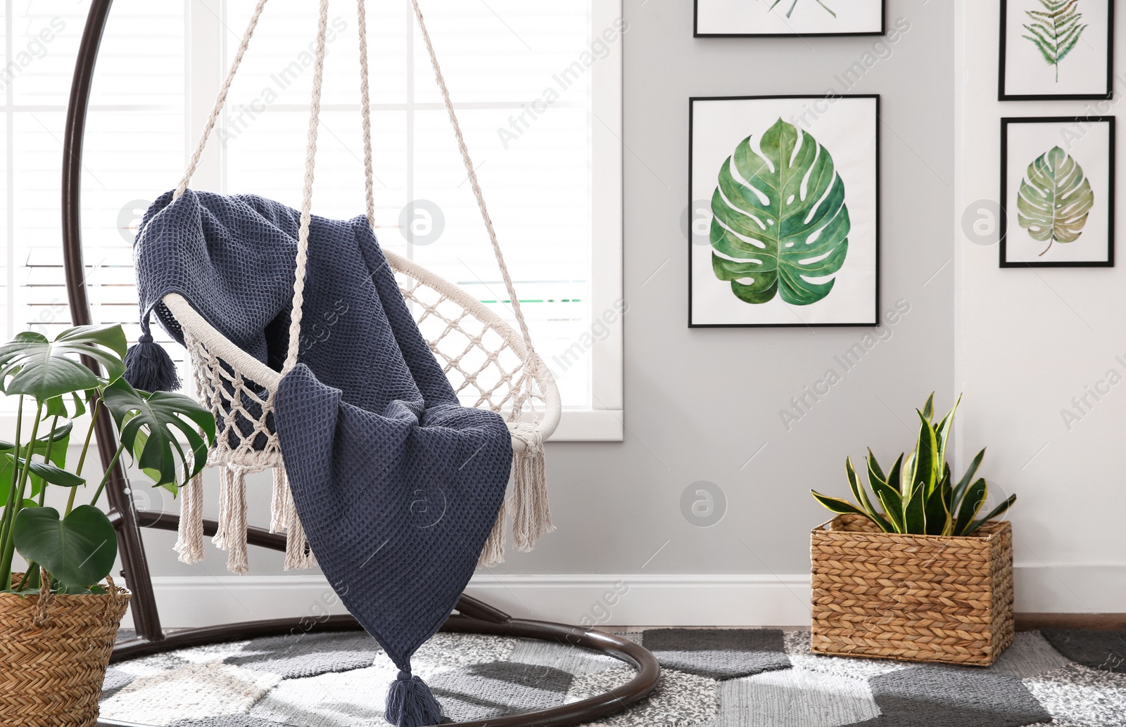 Photo of Stylish room interior with artworks and hanging chair