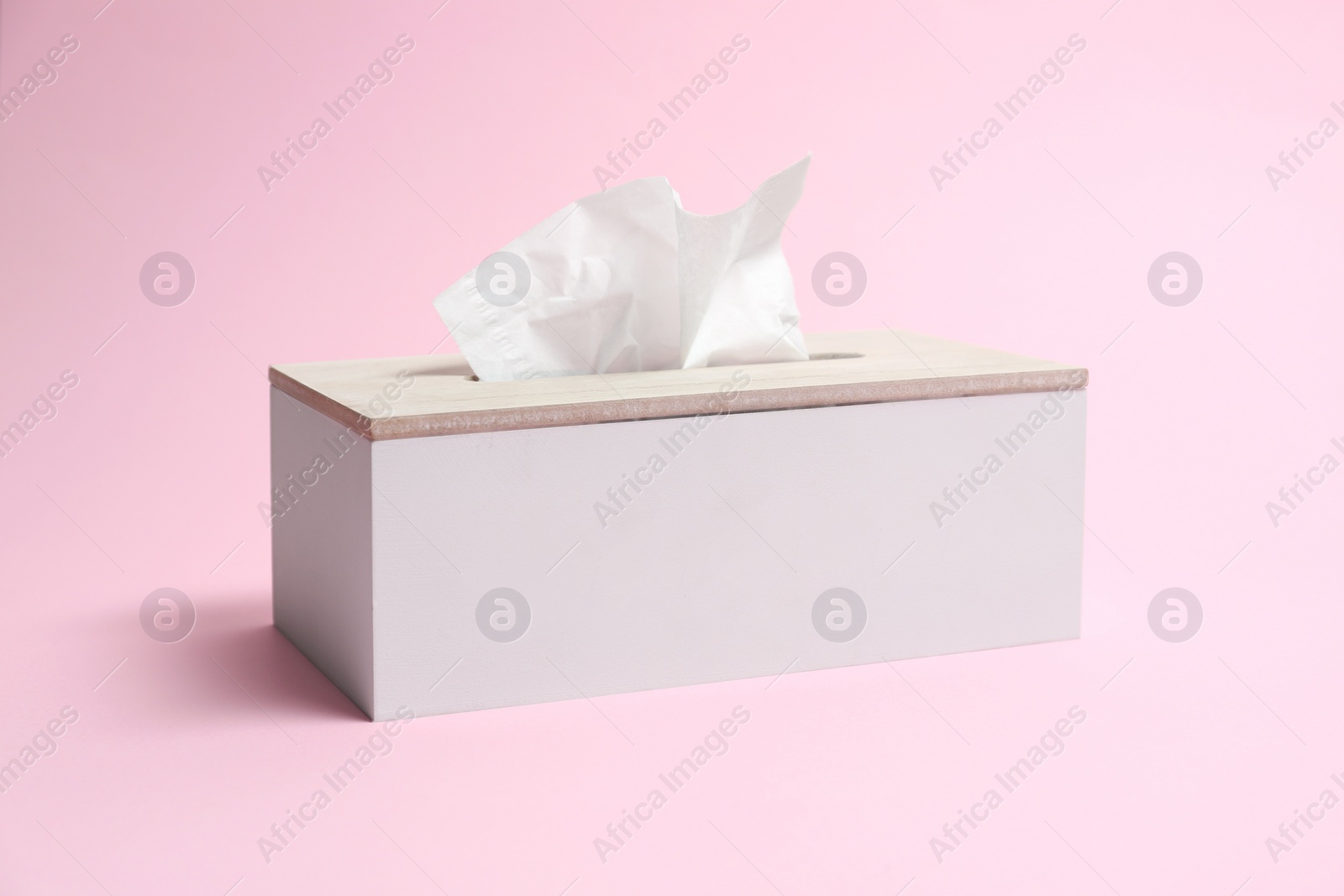 Photo of Holder with paper tissues on pink background