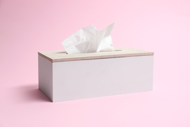 Photo of Holder with paper tissues on pink background