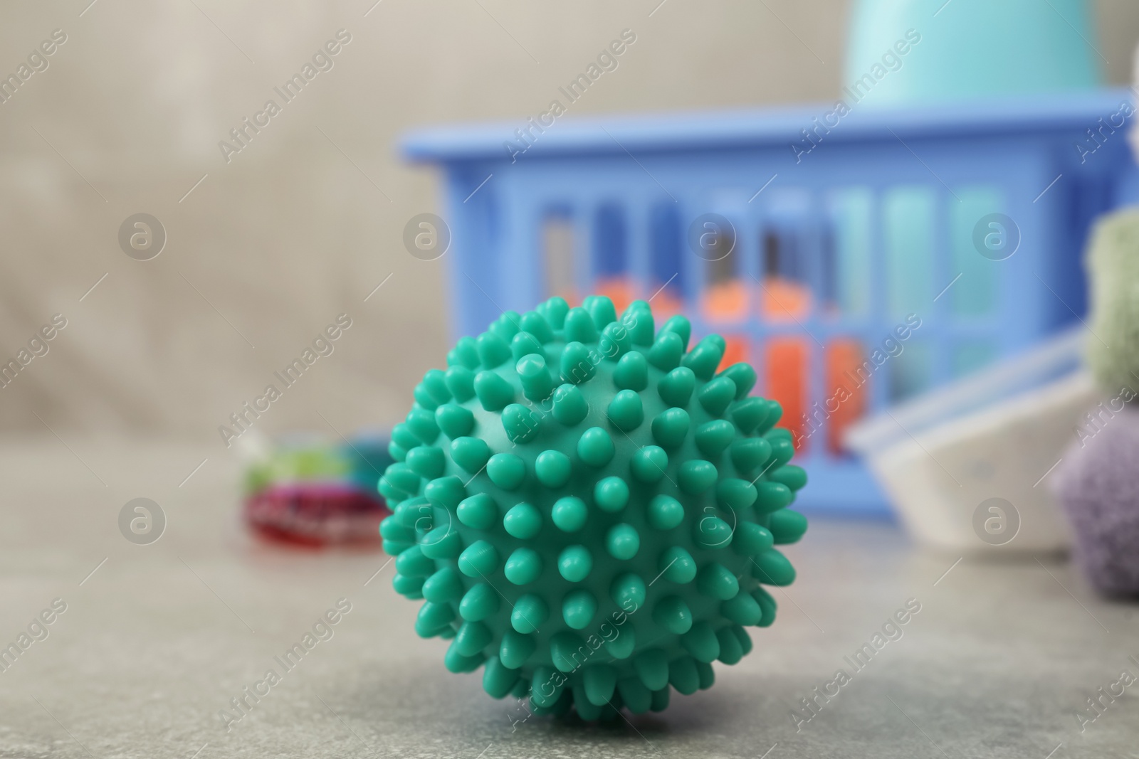 Photo of Turquoise dryer ball on grey marble table, closeup