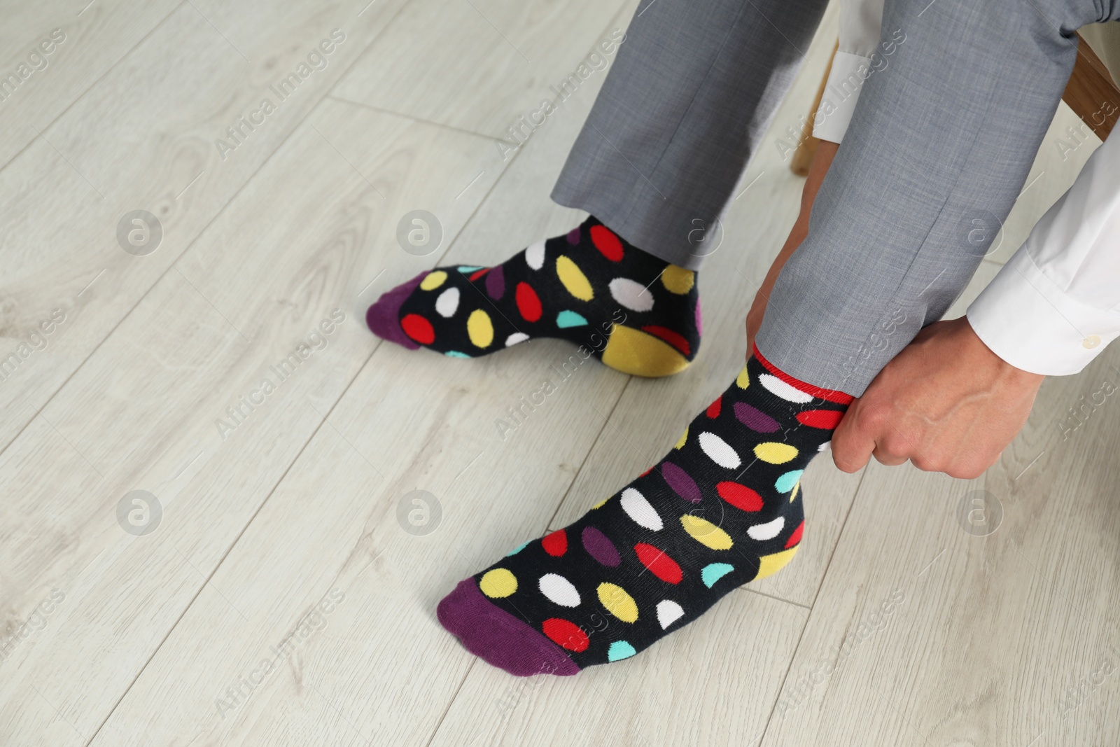 Photo of Man putting on colorful socks indoors, closeup