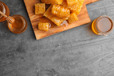 Flat lay composition with delicious honey on grey table. Space for text