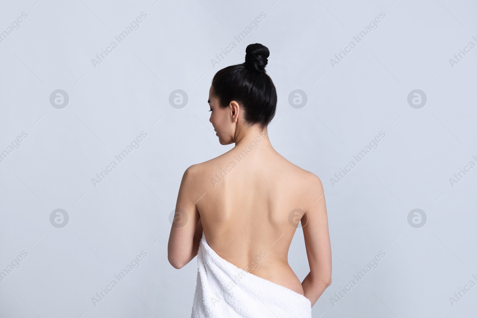 Photo of Back view of woman with perfect smooth skin on light background