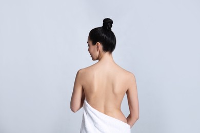 Back view of woman with perfect smooth skin on light background