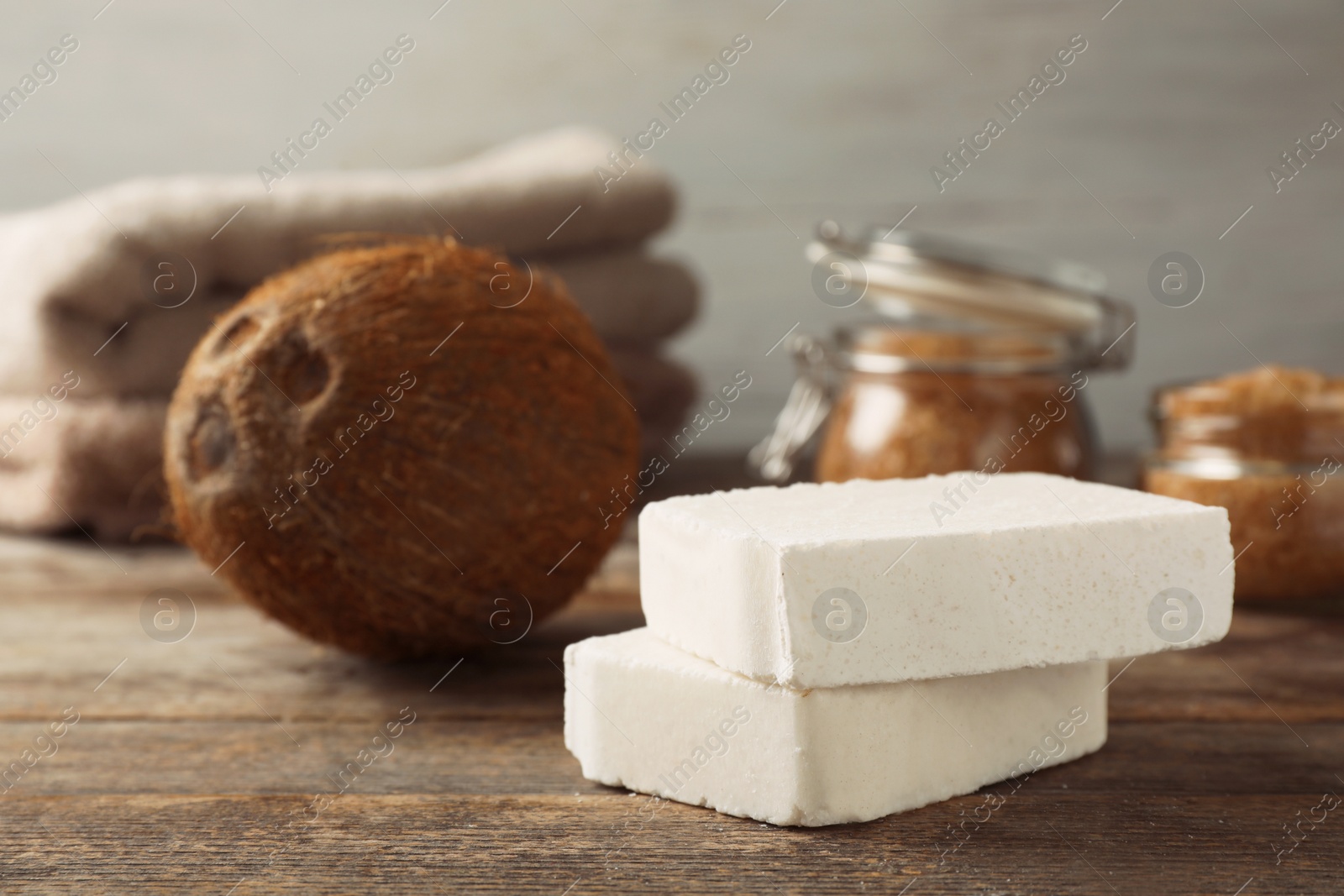 Photo of Handmade soap bars and coconut on wooden table. Space for text