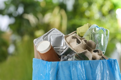 Trash bin with garbage on blurred background, space for text. Recycling problem