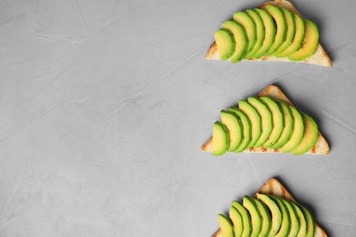 Photo of Tasty toasts with avocado on light grey table, flat lay. Space for text