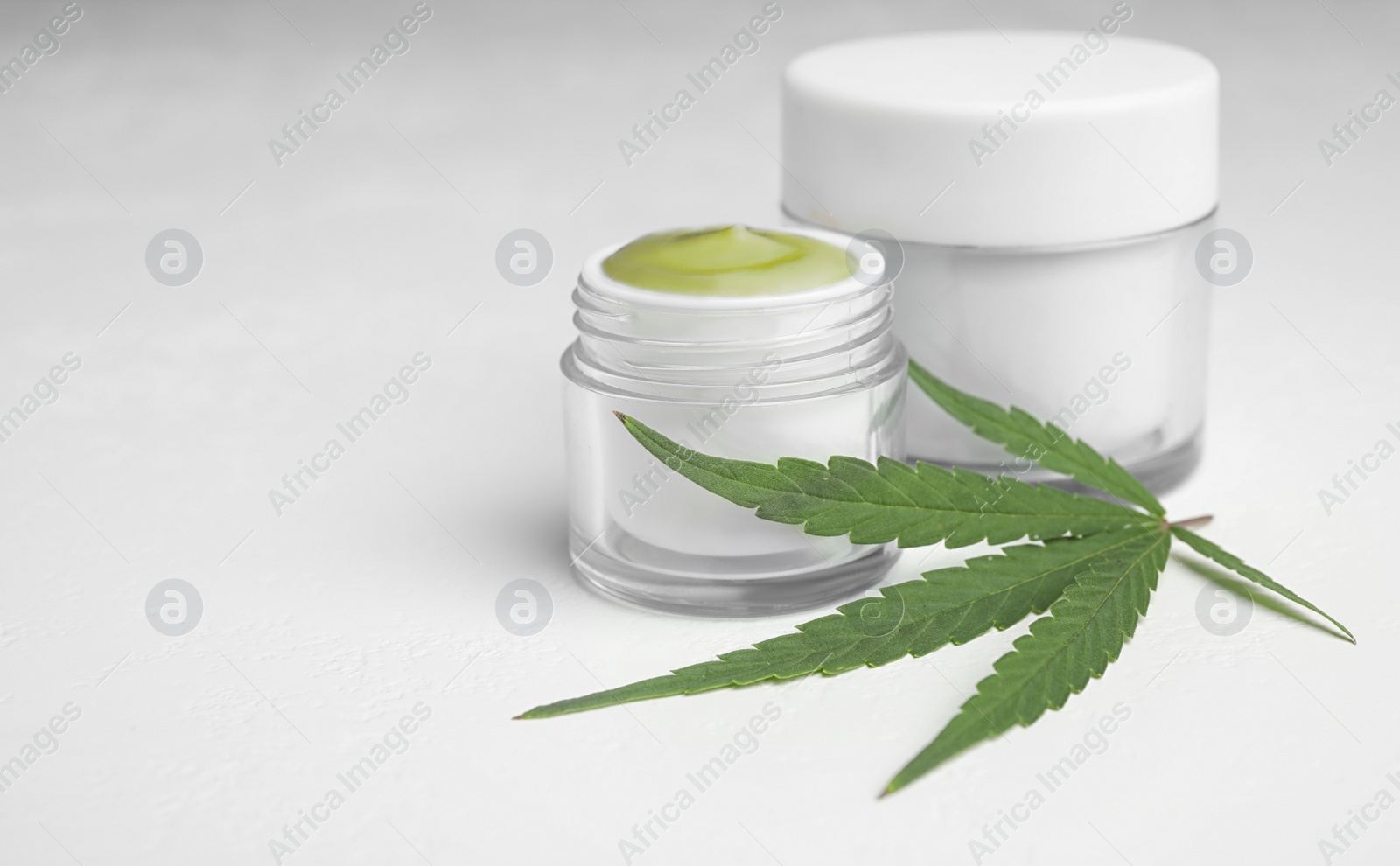 Photo of Jars of hemp cream on white table, space for text. Organic cosmetics