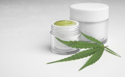 Jars of hemp cream on white table, space for text. Organic cosmetics