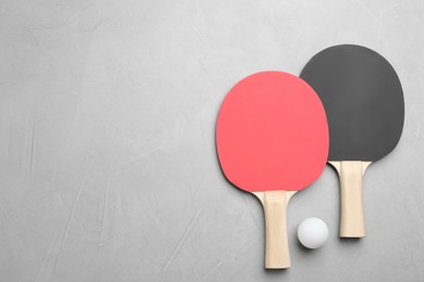 Photo of Ping pong rackets and ball on grey table, flat lay. Space for text