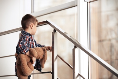 Sad little boy with toy on stairs indoors