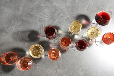 Different glasses with wine on grey background, flat lay