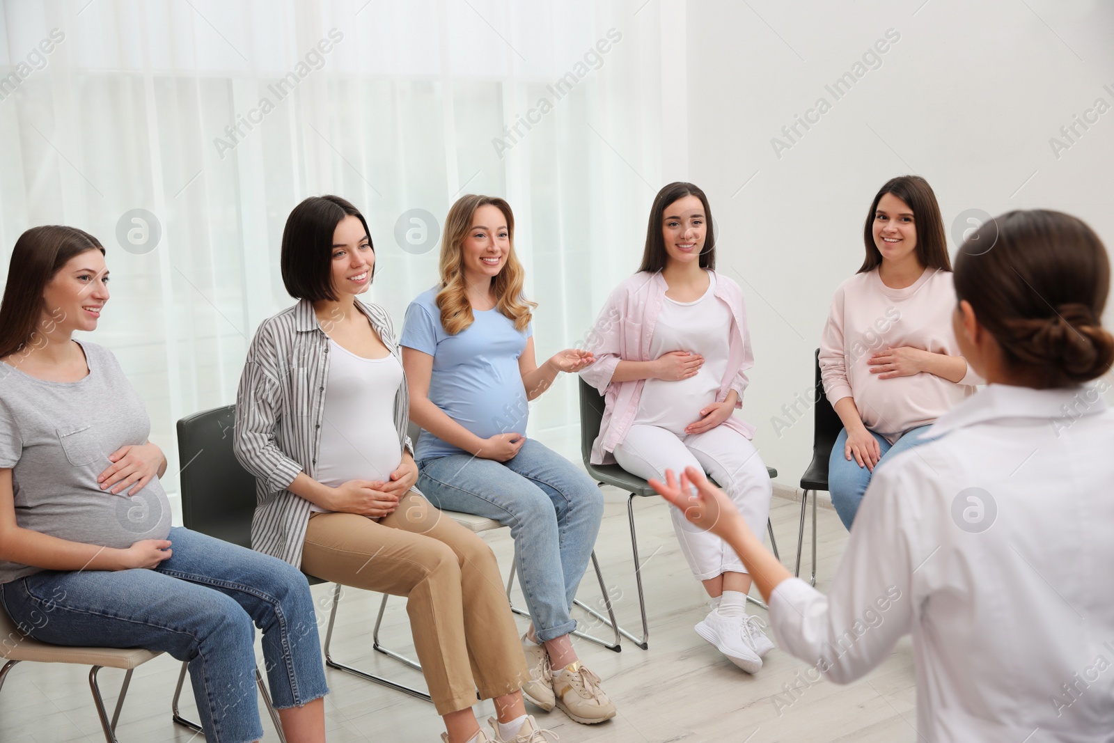 Photo of Group of pregnant women with doctor at courses for expectant mothers indoors