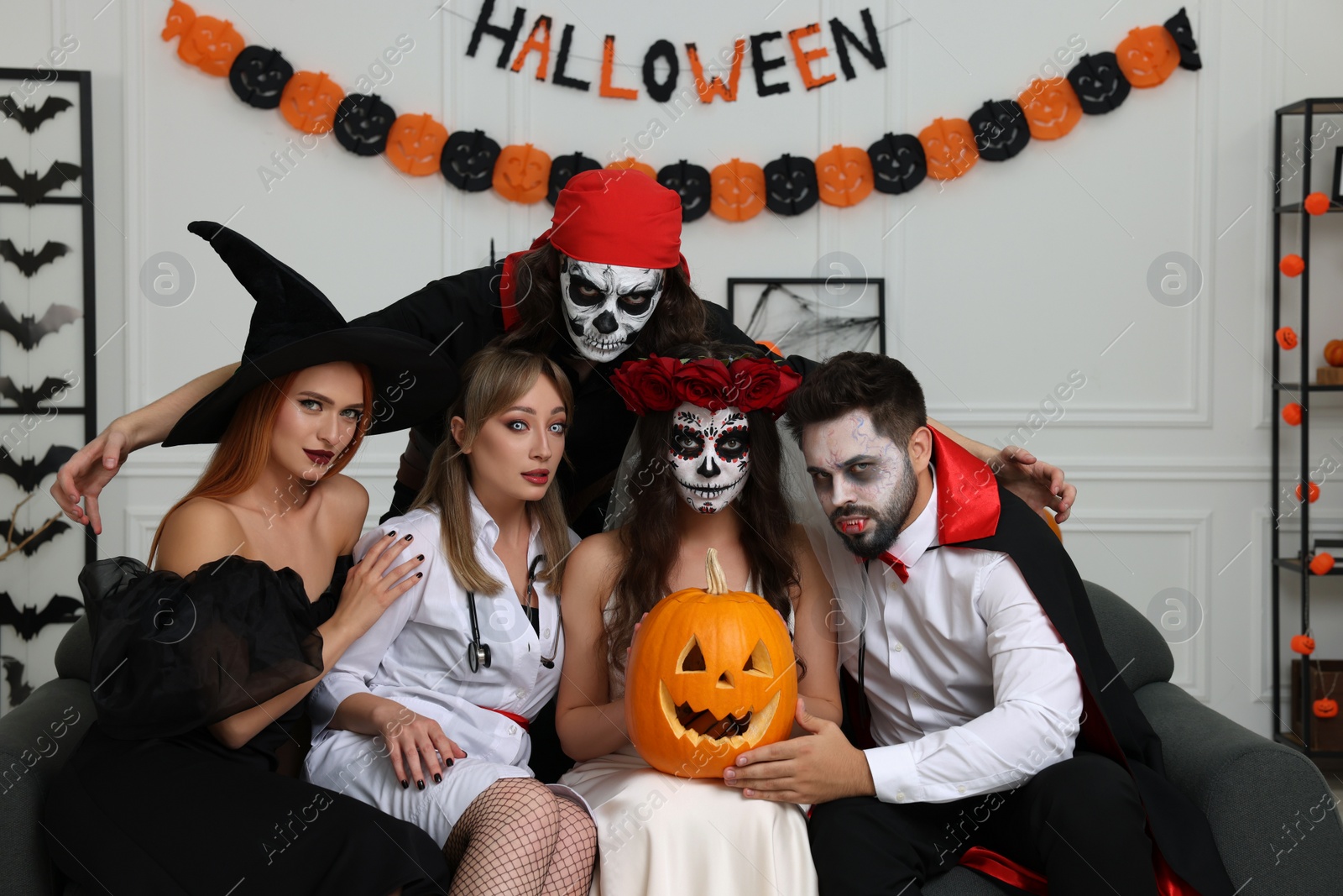 Photo of Group of people in scary costumes with carved pumpkin indoors. Halloween celebration