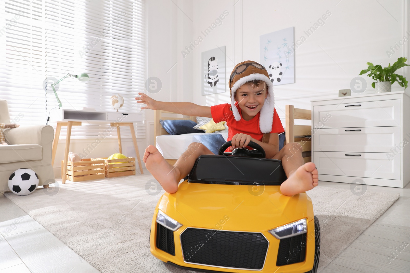 Photo of Cute little boy driving big toy car at home