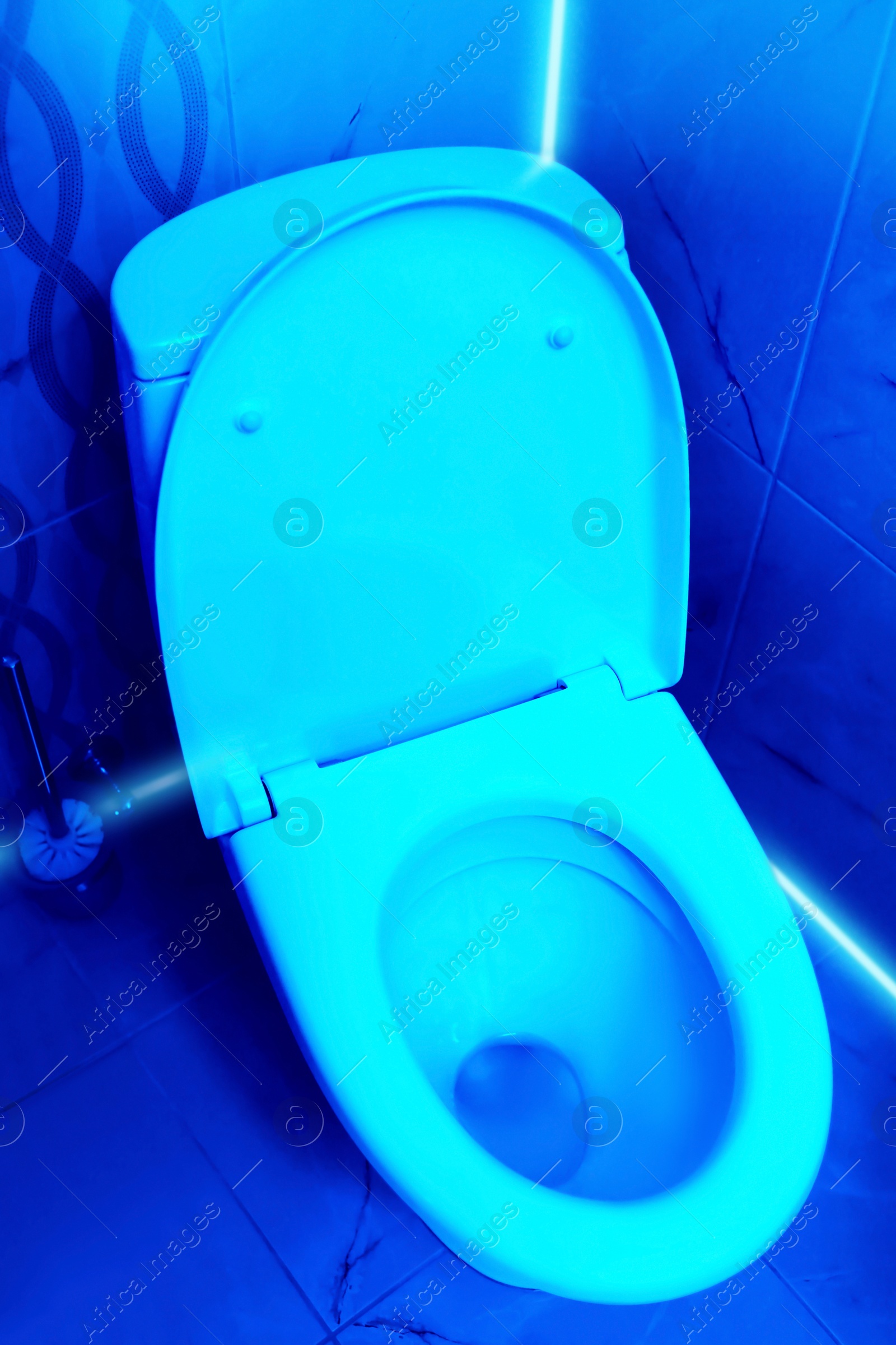 Image of Toilet bowl in public restroom lit with UV blue light