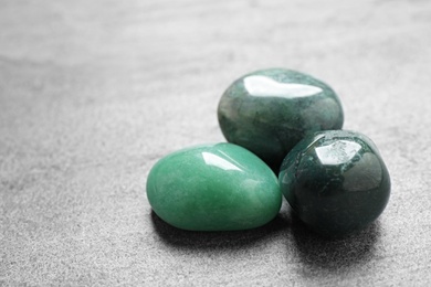 Photo of Beautiful green gemstones on grey table, space for text