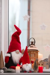 Cute Christmas gnomes and other festive decorations on windowsill in room
