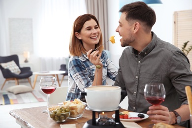 Photo of Happy couple enjoying fondue dinner at home